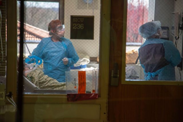 Photograph of medical staff in full personal protective equipment in a patient's room